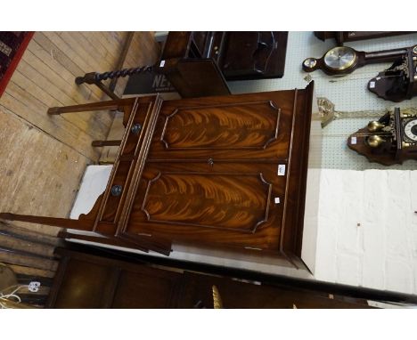 A reproduction George III style feathered mahogany finished drinks cabinet, the twin panelled doors enclosing a satin finishe