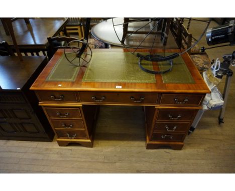 A reproduction Victorian-style mahogany veneered pedestal desk, with inset gilt tooled green leather writing surface, above a