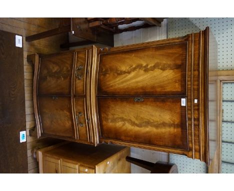 A reproduction Georgian style cross banded feathered mahogany veneered serpentine fronted tall drinks cabinet, having two upp