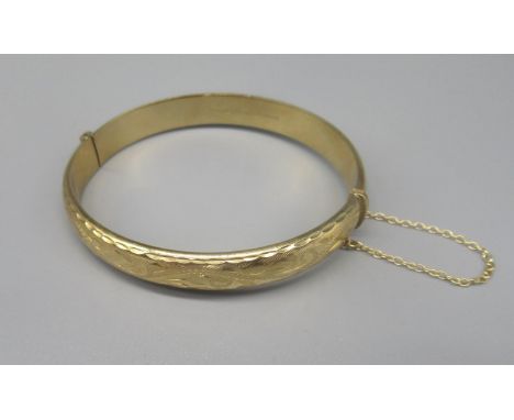 9ct yellow gold hinged bangle with engraved design and safety chain, stamped 375, 10.2g 