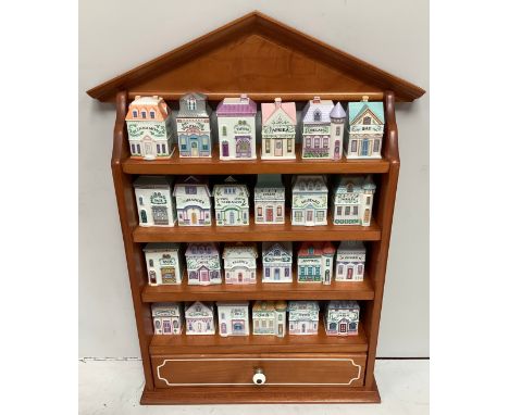 A decorative spice rack by Brooks and Bentley consisting of 24 ceramic house-shaped containers individually marked with vario