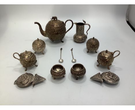 An Indian white metal six piece condiment set   with embossed foliate decoration, together with a similar small teapot with e