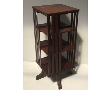 An early 20th century walnut revolving bookcase with three shelves on all four sides and slatted vertical panels, label to th