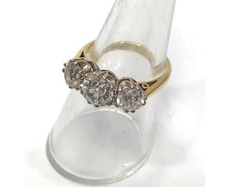 An 18ct yellow gold three stone diamond ring, the centre victorian cut diamond estimated 1.30cts, flanked by two round victor