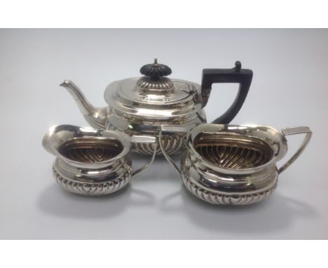 A late Victorian three-piece silver tea set, of compressed oblong 'Regency Style' with half-gadrooned body, ebonised finial t