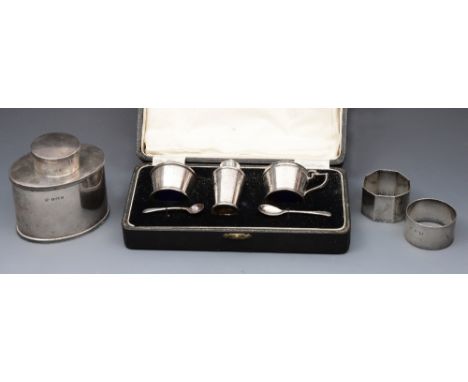 A CASED THREE PIECE SILVER CRUET SET of Art Deco design consisting of a mustard and salt with blue glass liners, a pepper and