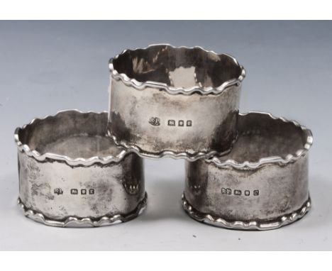 A SET OF THREE SILVER NAPKIN RINGS with Chippendale style edges, two London 1932, and one 1958 by Robert Pringle & Sons, 2.7 
