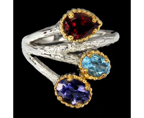A 925 silver ring set with garnet, tanzanite and blue topaz.