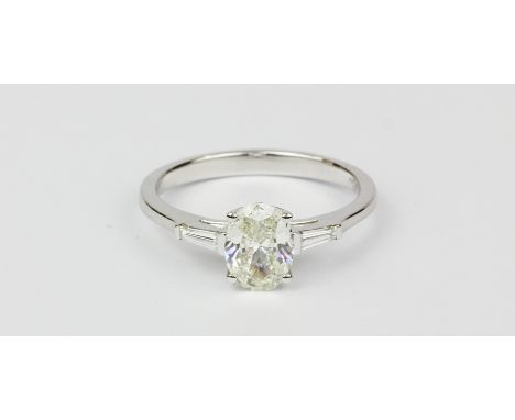 An 18ct white gold (stmaped 750) solitaire ring set with an oval cut diamond set ring, approx. 1.02ct, and tappered baguette 