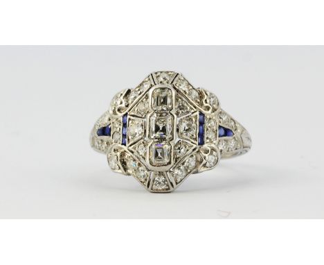 An Art Deco white metal (tested platinum) ring set with emerald and old brilliant cut diamonds and sapphires, approx. 1.40ct 