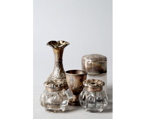 A pair of silver mounted glass inkwells, a silver mounted smelling salts jar, a silver baluster shaped vase with engraved flo