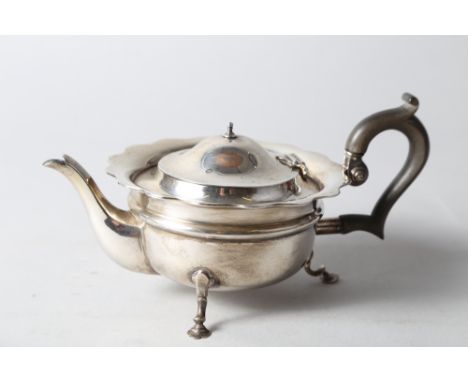A silver squat teapot with waved rim and ebonised handle, on three cabriole supports, 12.7oz troy approx 