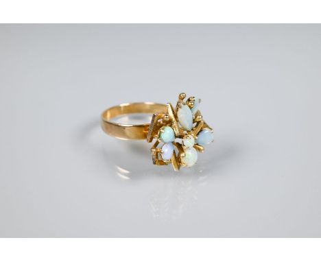 An opal cluster ring, the stylised angular open work setting with seven oval opals, on wide flat shank, size Q, yellow metal 