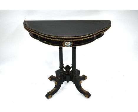 A French brass inlaid and mounted ebonised demi-lune card table, 19th century, with fold over top, raised on four columns and