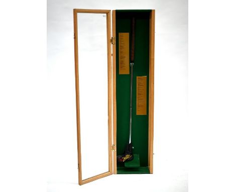 An Arnold Palmer golf putter with leather cover, signed on grip, in glazed display case with Palmer's playing record