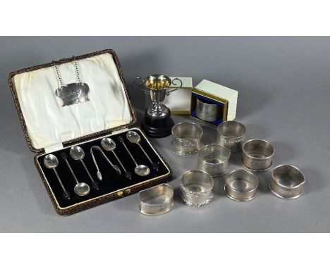 Nine various silver napkin rings to/w a Port decanter label, miniature trophy cup and a cased set of six coffee spoons with b