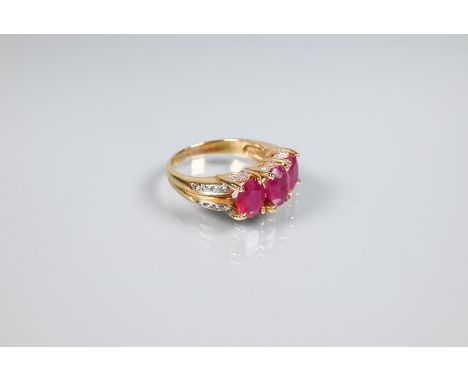 A ruby ring, the three oval rubies claw set, with diamond set gallery and split shoulders, yellow metal set, unmarked and unt
