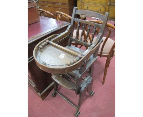 An Early XX  Century Walnut Child's Convertible High Chair, with drop down tray and bauble ring, spindle back and cogged mech