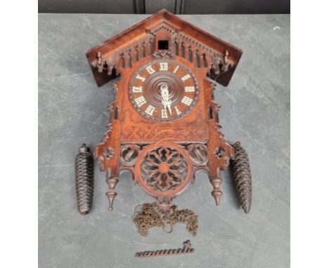 A Black Forrest carved oak cuckoo clock, 51cm high, (mechanism incomplete), with pendulum and pinecone weights.