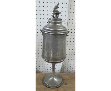 A pewter standing cup and cover, the finial modelled as a crouching soldier, engraved with chariots, height 15.25ins