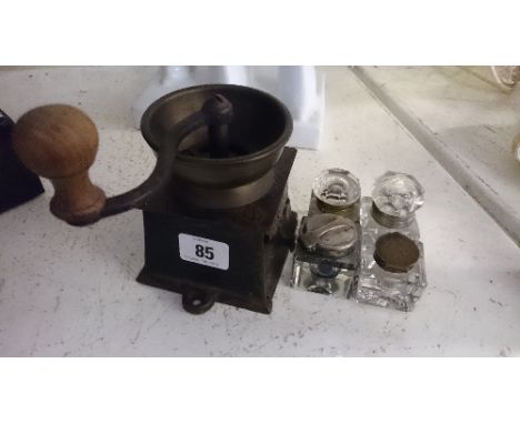 Four small glass inkwells together with a Kenrick iron coffee grinder.