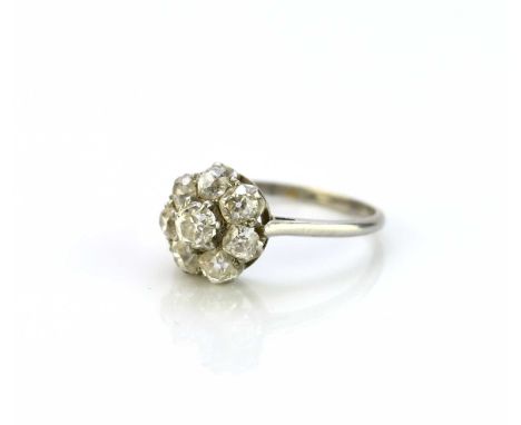A diamond floral cluster ring, designed as a central old cut diamond claw set in white metal within a border of seven old and