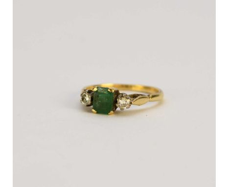 An emerald and diamond ring, designed as a central rectangular cut emerald flanked to each side by a brilliant cut diamond, t