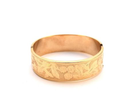 A yellow metal bright cut engraved hinged bangle, with push clasp with attached safety catch, stamped ‘585 BH’, inner diamete