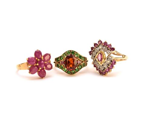 A spessartite garnet ring, the yellow metal shank stamped '585', size M, together with two untested ruby rings, both stamped 
