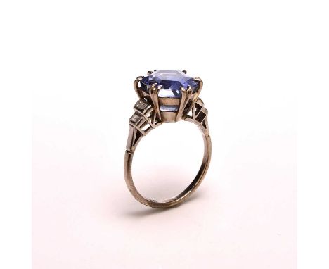 A sapphire and diamond ring, designed as a central hexagonal cut sapphire claw set in white metal and flanked to each side by