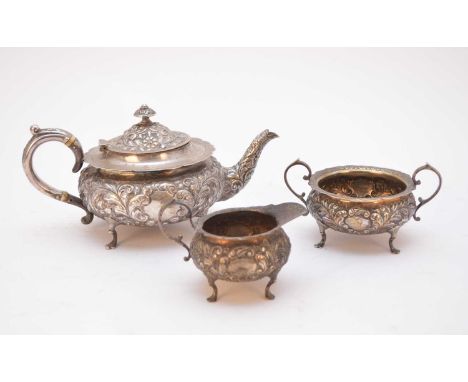 A matched three piece silver tea service, each piece of circular form with embossed scroll decoration, cusped rim and raised 