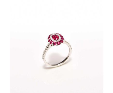 A ruby and diamond cluster ring, designed as a central oval mixed cut ruby claw set in white metal within an inner border of 
