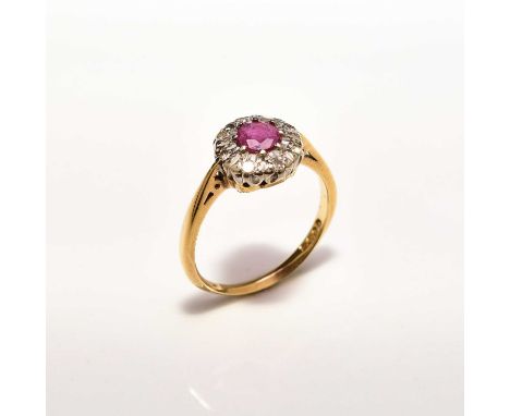 An 18ct gold ruby and diamond floral cluster ring, designed as a central round mixed cut ruby claw set in white gold within a