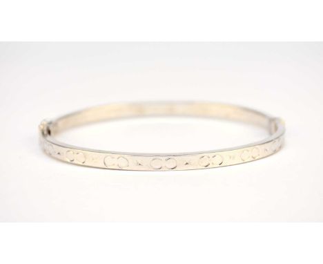 A white metal hinged bangle, the spring driven pin clasp with attached safety catch, stamped '375', weight approx 5.8g