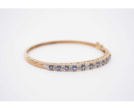 A 9ct gold untested sapphire and diamond hinged bangle, the gradutated round mixed cut sapphires each interspersed with pairs