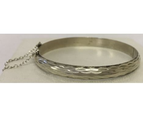 A vintage silver hinged bangle with engine turned decoration and safety chain.Inside of bangle marked 925 with makers initial