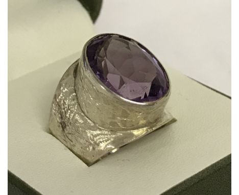 A vintage silver dress ring set with a large oval cut amethyst.Crackle decoration to mount and band. Hallmarked London 1977.S