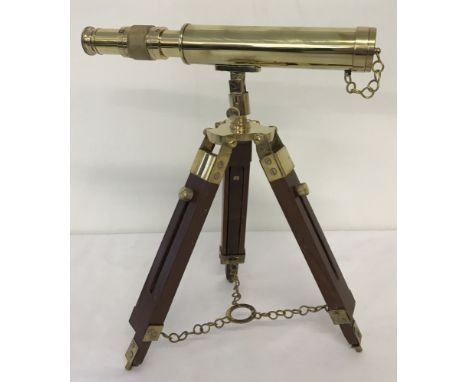 A small brass telescope together with a wooden and brass tripod stand.Telescope approx. 24.5cm long.