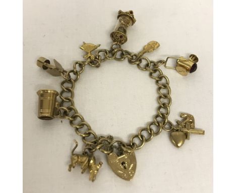 A 9ct gold charm bracelet with decorative padlock, safety chain and 8 charms.Hallmark to each bracelet link, padlock and all 