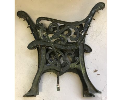 A pair of decorative cast iron bench ends, painted dark green.
