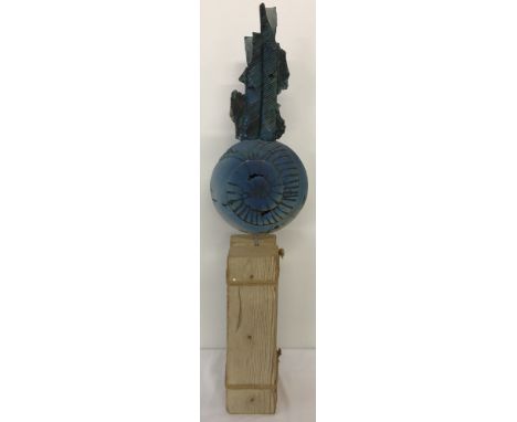 A modern ceramic sculpture of an ammonite mounted on rustic wood plinth.Approx. 84cm tall.
