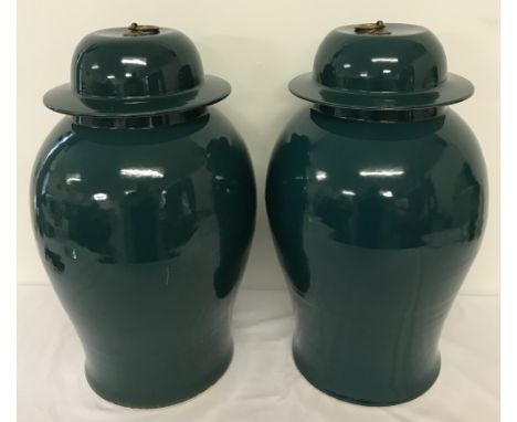 A pair of green ceramic oriental temple jars with brass ring shaped finials to lids.Approx. 50cm tall.