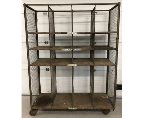 A large vintage metal laundry rack on wheels.With enamel labels to shelves and mesh divisions.Approx. H186cm x W140cm x D50cm