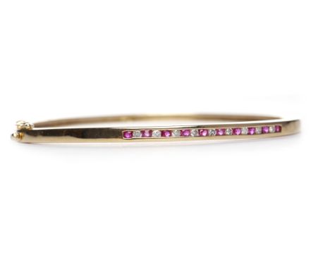 RUBY AND DIAMOND SET BANGLEof oval form and with a row of channel set round brilliant cut diamonds interspaced by round rubie