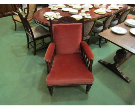 A circa 1900 walnut armchair with carved and reeded decoration, turned arm supports over turned legs and ceramic castors