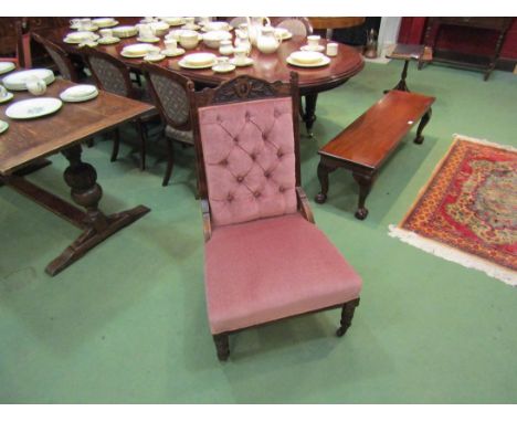 An Edwardian walnut button back open armchair with carved decoration over turned legs and ceramic castors 