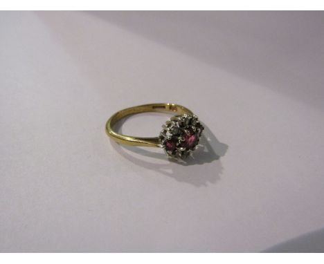 A 9ct gold ring set with three rubies enclosed by six individually set diamonds. Size O/P, 2.4g