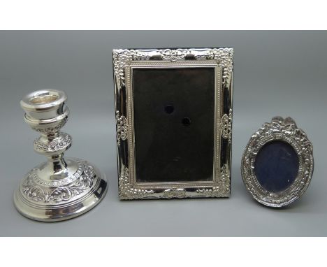 A silver candlestick and two photograph frames 