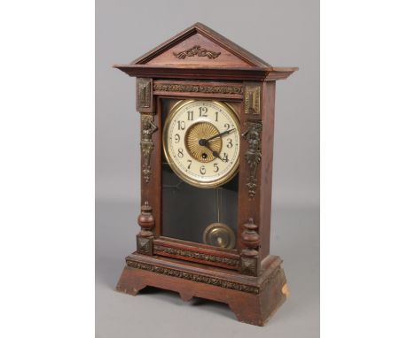 A wooden cased mantel clock with Arabic numeral markers. With pendulum and key.  