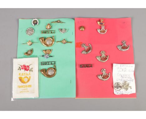 A collection of military cap badges and pins including King's Own Yorkshire Light Infantry, Royal Irish Rifles and King's Shr